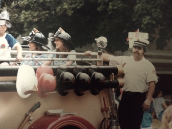 Denny Wilson4 standing on the back of a fire truck in a parade
